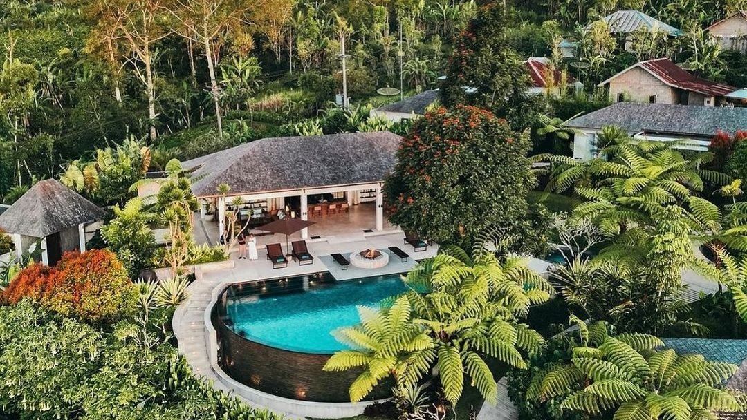 Aerial view of Alta Vista Mountain Villa Bali with curved infinity pool and tropical jungle surroundings