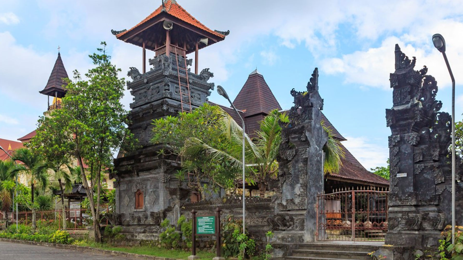 Puja Mandala religious complex in Nusa Dua Bali showing Balinese temple gate tower and nearby church buildings surrounded by trees