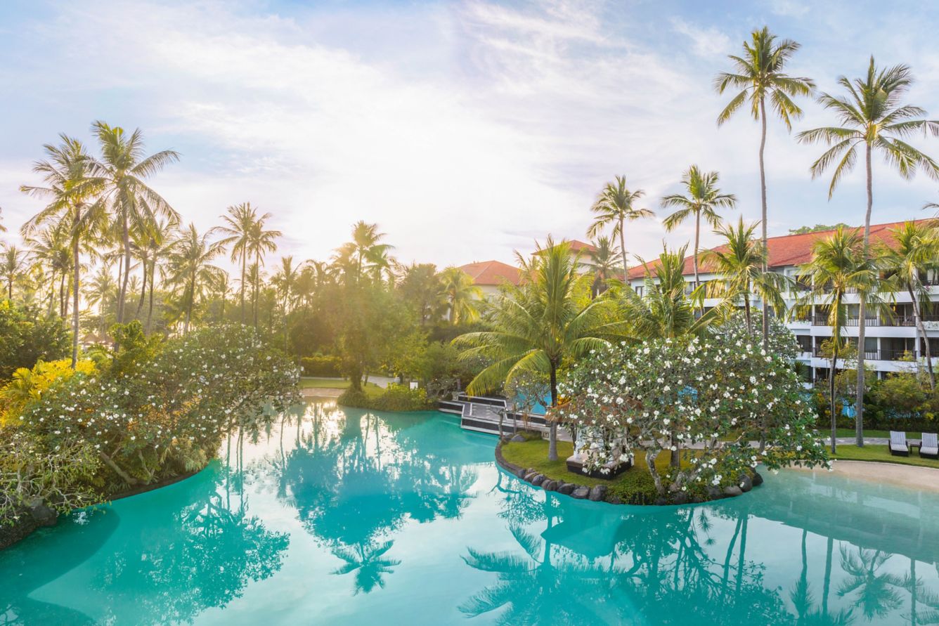 Lagoon style swimming pool surrounded by palm trees at The Laguna Luxury Collection Resort Nusa Dua Bali