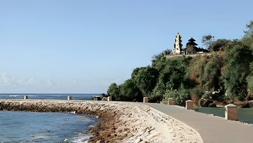 Pura Geger temple on a green cliff above the ocean in Nusa Dua Bali with a paved path along the shoreline