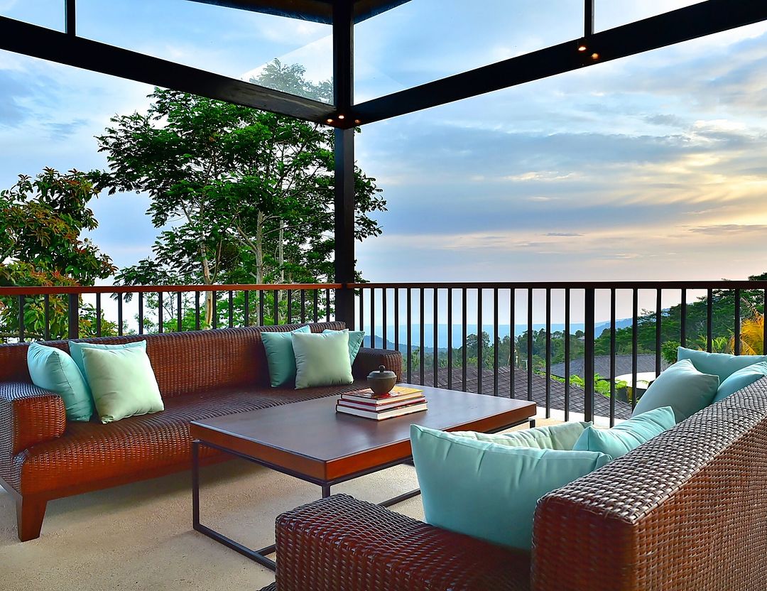 Teras luar Alta Vista Mountain Villa Bali dengan tempat duduk rotan dan pemandangan lembah