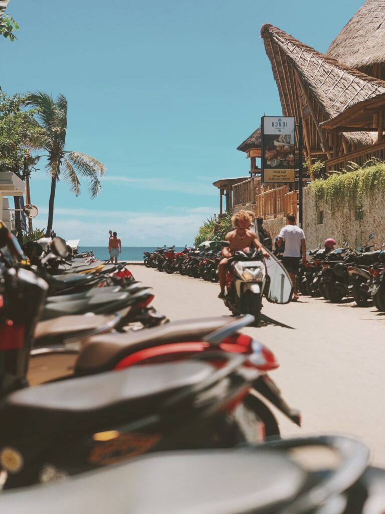 Bali beach street lined with scooters and thatched-roof cafés