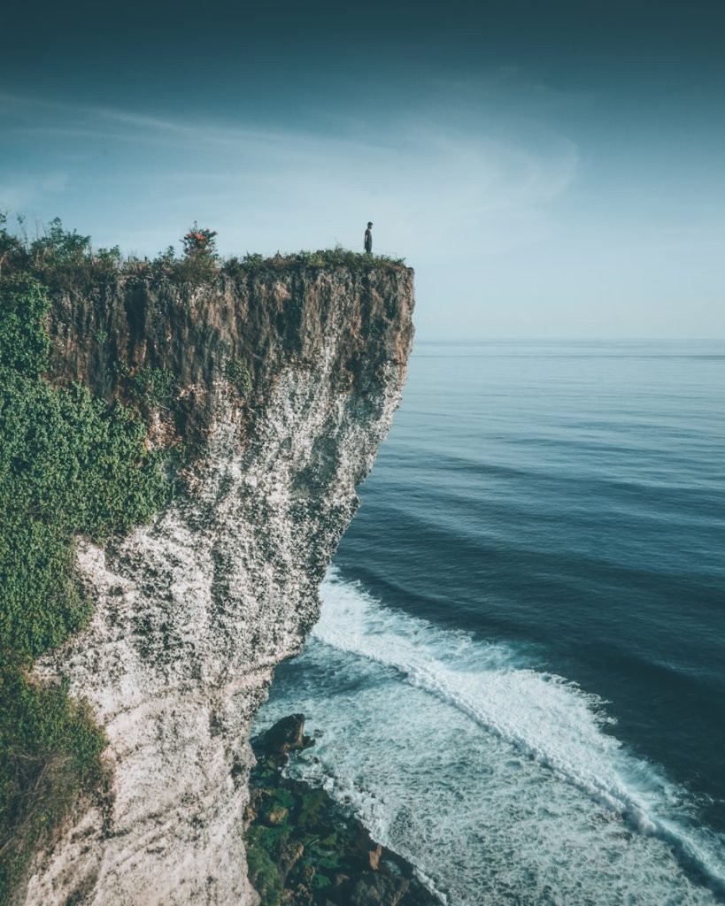 a person standing on top of karang boma cliff