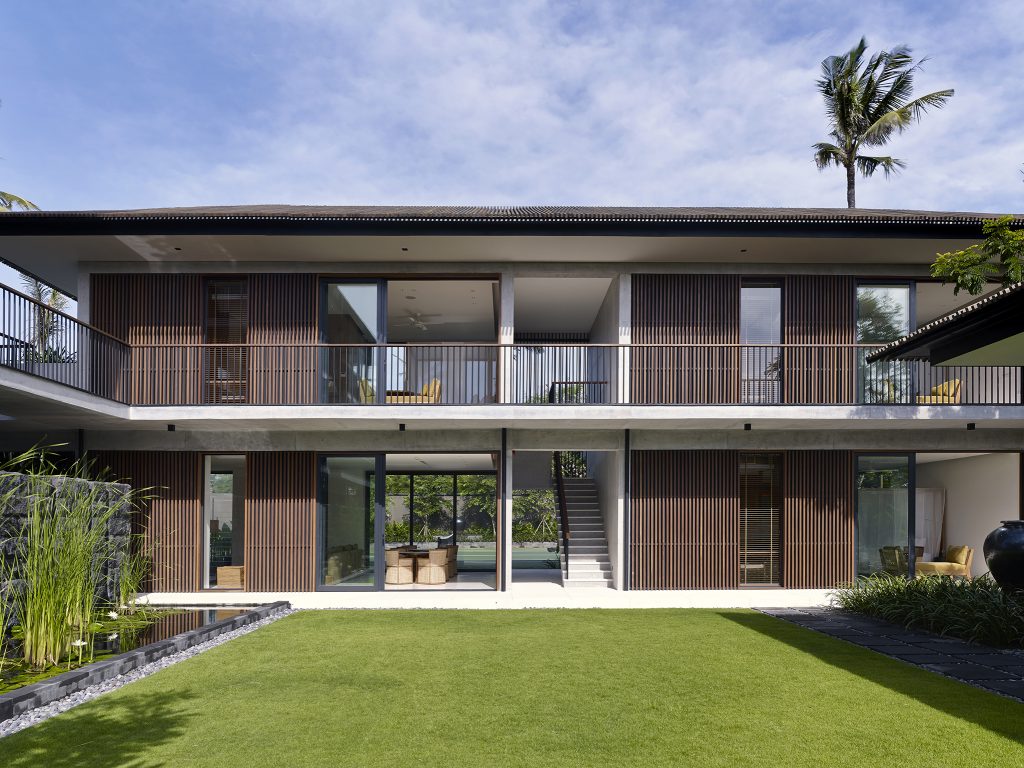 Arnalaya Beach House at Nelayan Beach modern two story villa with balcony rooms facing a wide grass lawn