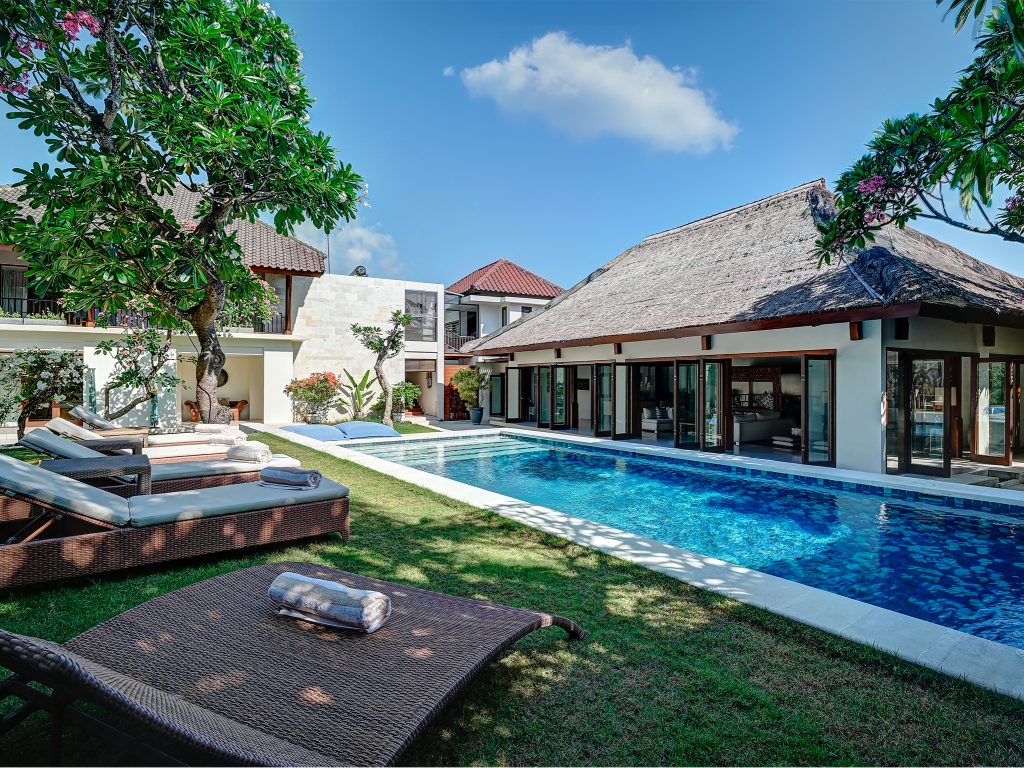Villa Casa Evaliza Seminyak villa with long blue pool grass lawn sun loungers and leafy trees