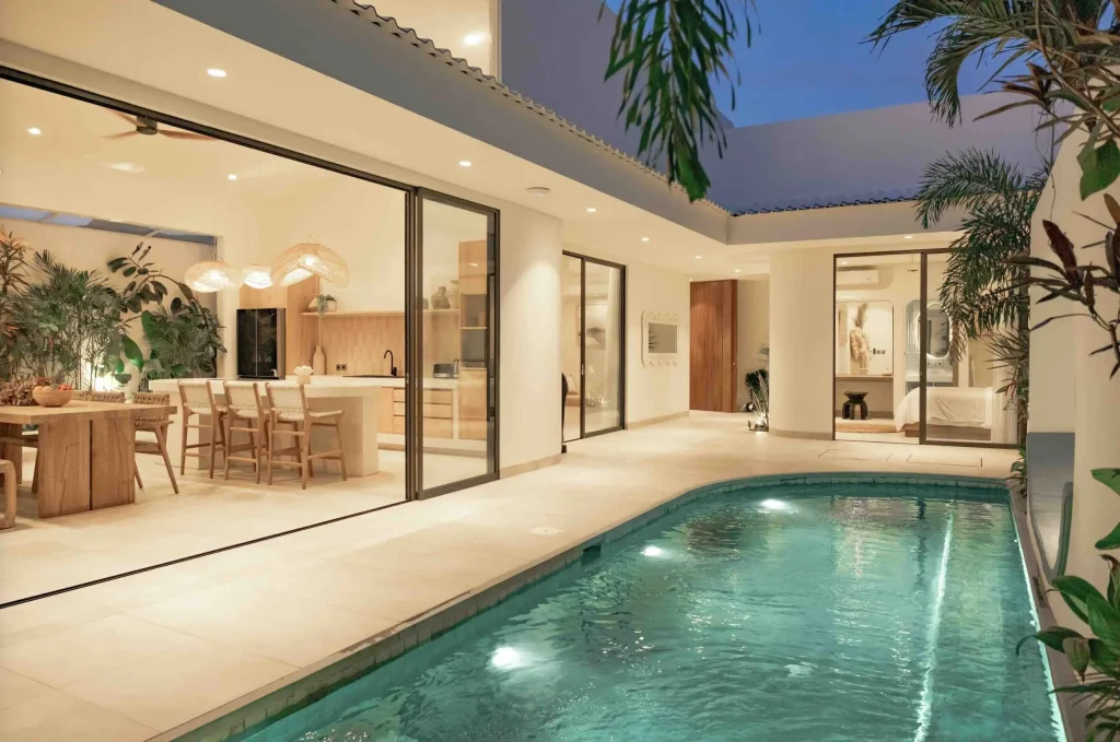 Villa Curl Curl in Berawa Canggu with private pool and open plan living and dining area lit up at night