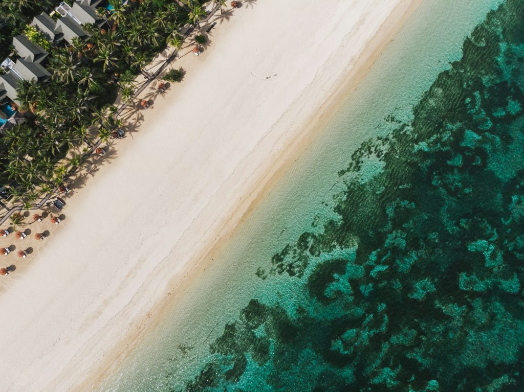 Aerial view of Geger Beach in Nusa Dua Bali with white sand, turquoise water and palm lined resort