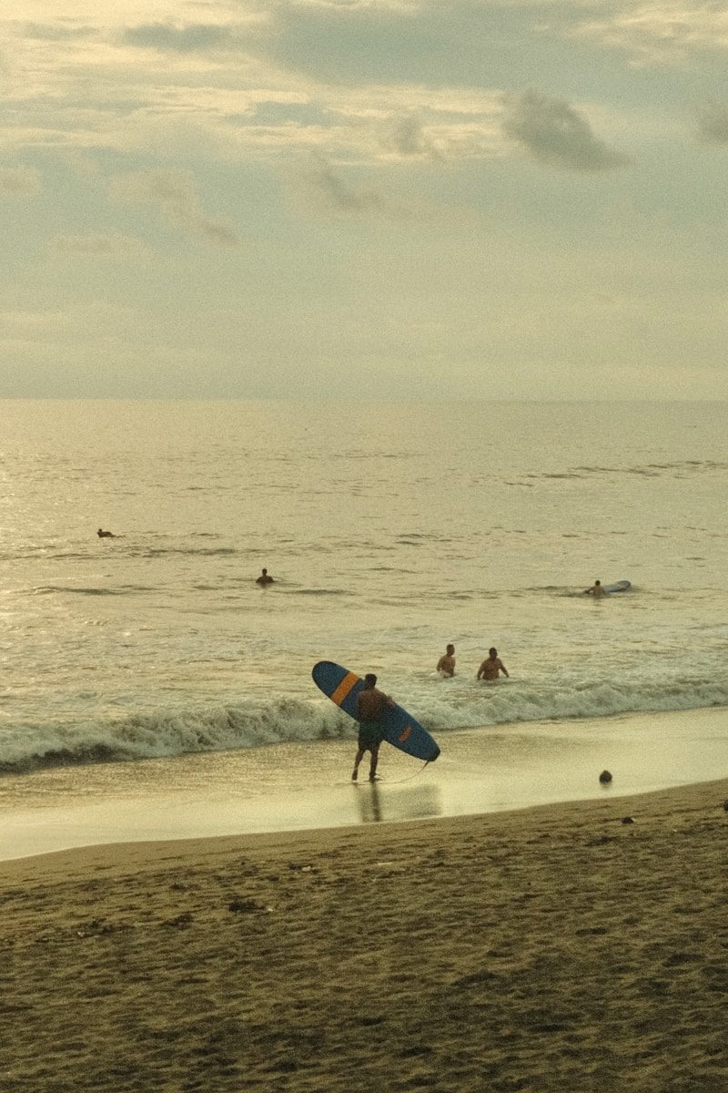 Peselancar berjalan di sepanjang Pantai Seminyak Bali