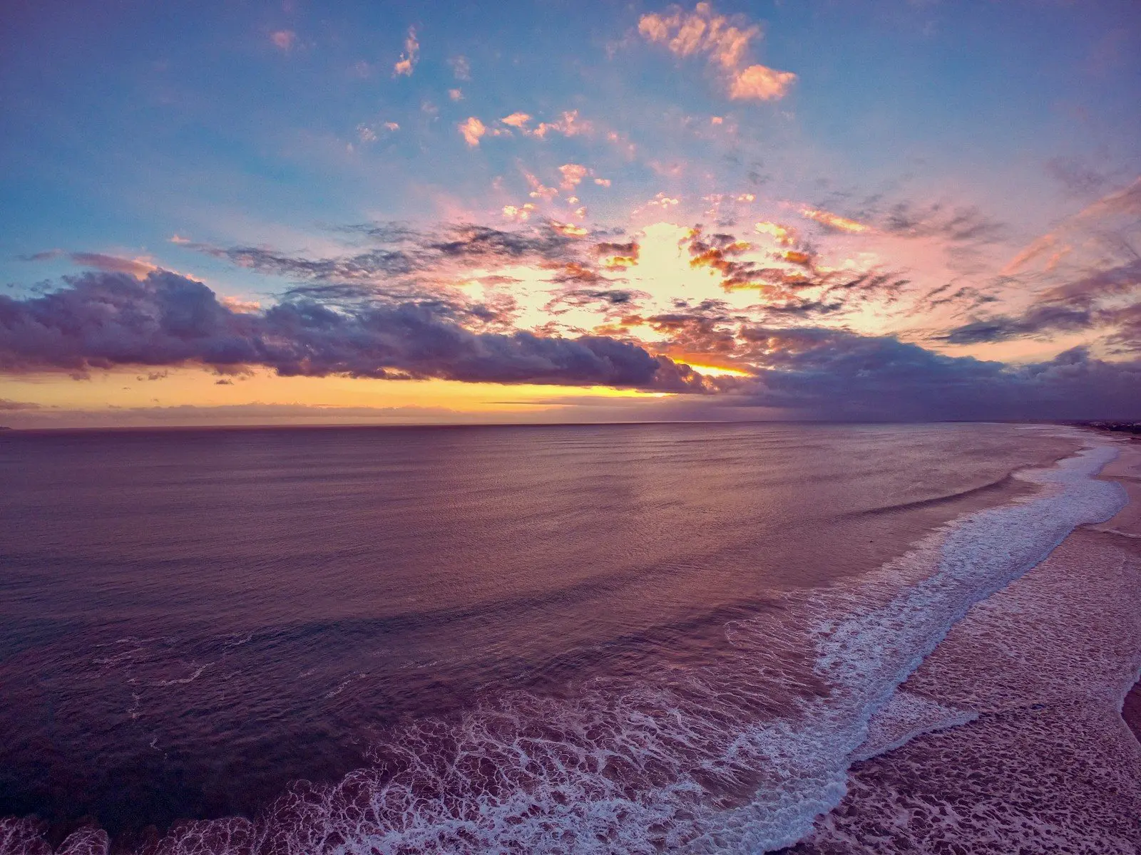 Ombak menuju Pantai Seminyak saat matahari terbenam di Bali