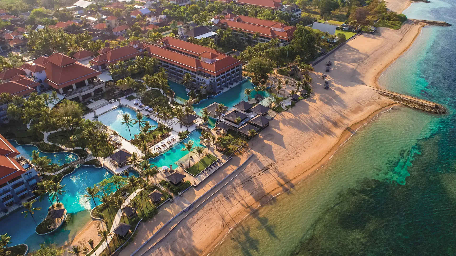 Aerial view of Conrad Bali with lagoon pools, tropical gardens and its beachfront in Nusa Dua